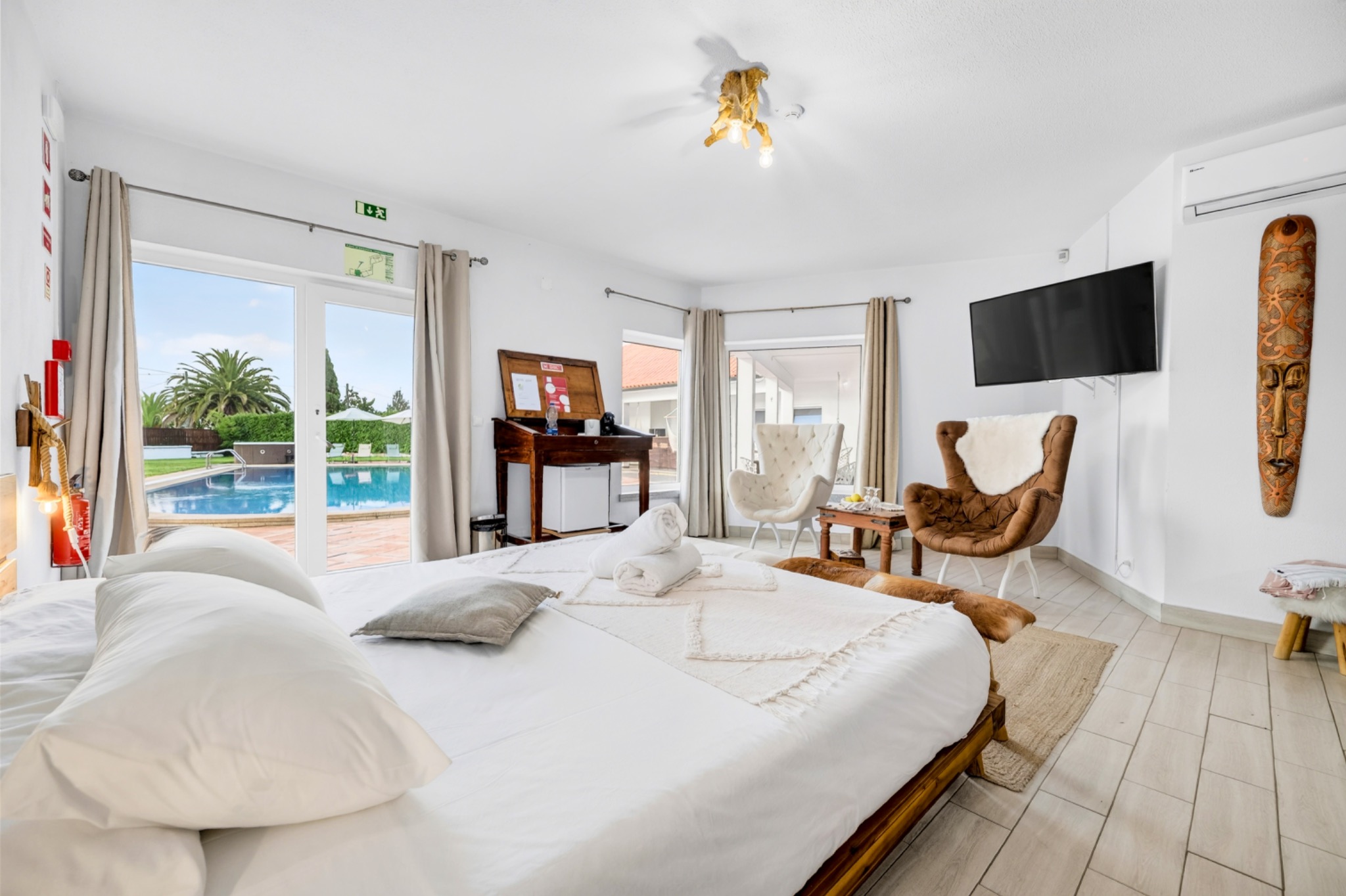 Bright poolside guest room with seating area and doors opening toward the swimming pool